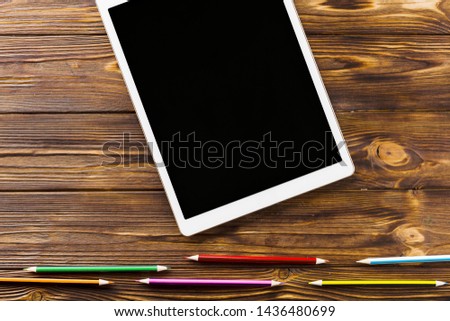 Pencils lying near tablet on wooden background
