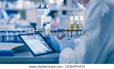 Senior Male Research Scientist is Using a Tablet Computer in a Modern High-Tech Laboratory. Genetics and Pharmaceutical Studies and Researches. Royalty-Free Stock Photo #1436495414