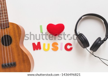 Love music text between the musical guitar and headphone on white background