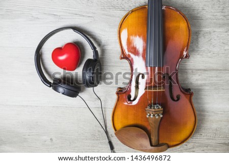 Elevated view of red heart surrounded with headphone and wooden classical guitar on gray table