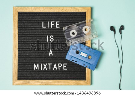 Transparent and blue cassette tape on message board with earphone on turquoise backdrop