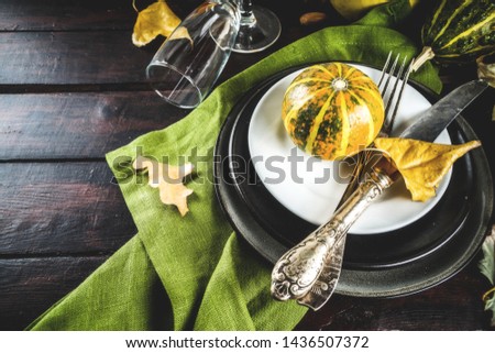 Autumn and thanksgiving celebration table setting. Flat-lay  with plates, silverware, glass and little pumpkins holiday decoration, wooden background, top view, copy space