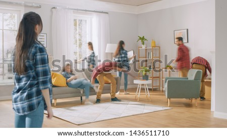 Time-Lapse Silhouettes or Blurred Happy Young Couple Moves into New Apartment, Arranges Furniture, Hanging Paintings, Resting on a Couch. Bright Modern House with Big Windows and Stylish Furniture. Royalty-Free Stock Photo #1436511710