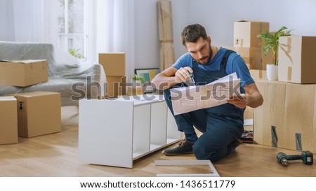 Successful Furniture Assembly Worker Reads Instructions to Assemble Shelf. Professional Handyman Doing Assembly Job Well, Helping People who Move into New House. Royalty-Free Stock Photo #1436511779
