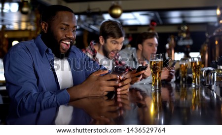 Afro-american man celebrating successful bet on match, online bookmaker on phone Royalty-Free Stock Photo #1436529764
