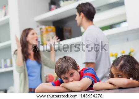 Couple arguing behind their children in the kitchen Royalty-Free Stock Photo #143654278