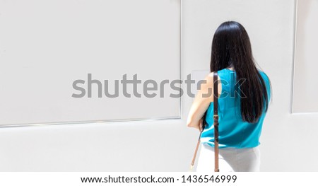 woman looking at white blank canvas on the wall in art gallery