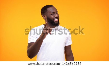 Smug afro-american man pointing finger camera and smiling yellow background Royalty-Free Stock Photo #1436562959