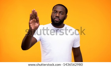 Young black guy showing stop gesture with palm on yellow background, rejection