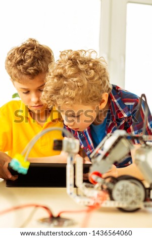 How does it work. Serious smart boys thinking about the robot while having a science class