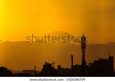 View through a window to silhouettes of buildings in front of Mt. Fuji during sunset 