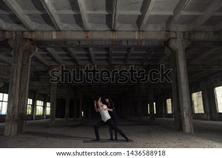 A young girl and boy perform acrobatic moves in the premises of an old factory, a warehouse, acro