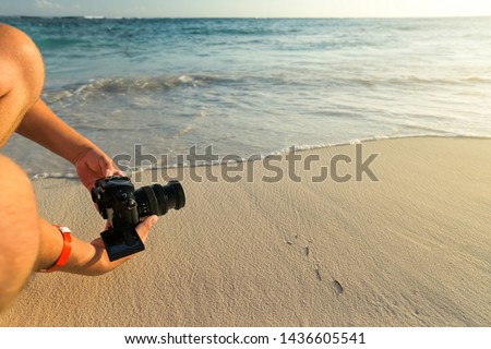 Closeup of tourist man on vacation shooting nature sunset by camera on sea background, copy space