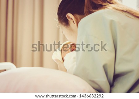 Selective focus of asian mother kissing newborn baby boy sleeping in hand at hospital
