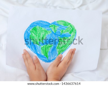 Hand holding picture heart world on white paper.Save the world, creative, environment pollution or World Earth Day concept. Top view