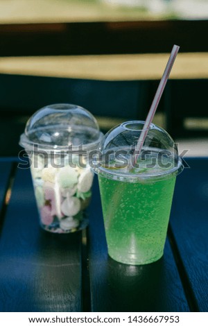 Green lemonade in a clear glass and sweets on wooden table