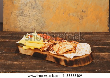 Doner kebab is lying on the cutting board. Shawarma with meat, onions, salad lies on a dark old wooden table