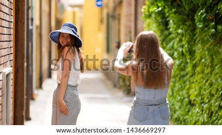 Two young women walking through the alleys - they take pictures of each other.