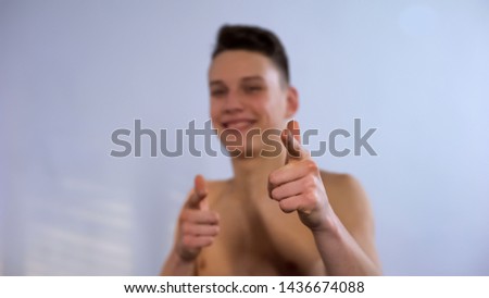 Smiling teenager making choose you gesture in bathroom, pretending to be cool