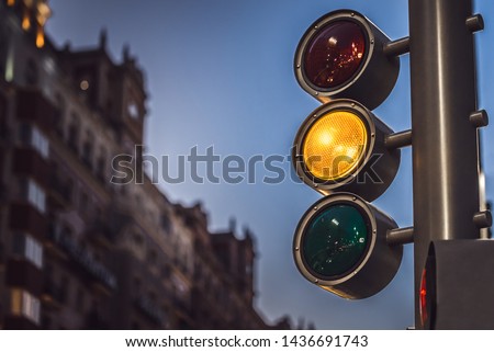 Modern Traffic light showing orange color at sunset night in a modern city
