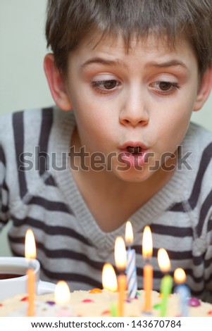 Young boy blowing out candles on a birthday cake