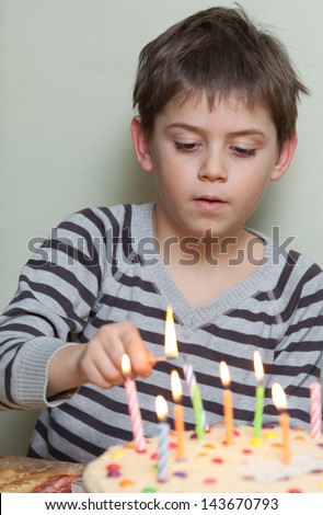 Kids celebrating birthday party and lighting candles on cake