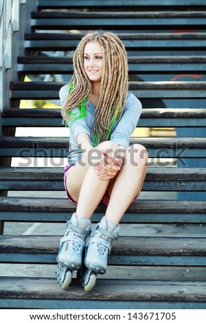 portrait of a beautiful girl with dreadlocks with rollerskates on her legs