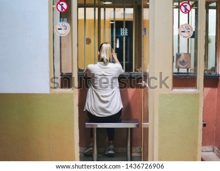 Young girl or woman looking forward to meeting a prisoner. Visiting booths in prison. Room for visitors to communicate with inmates at the jail Royalty-Free Stock Photo #1436726906