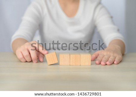 woman hand divide one of four blank wooden cube on table background. blank wood block for insert some sentence, icon, symbol, picture or meaningful word, idea and concept.