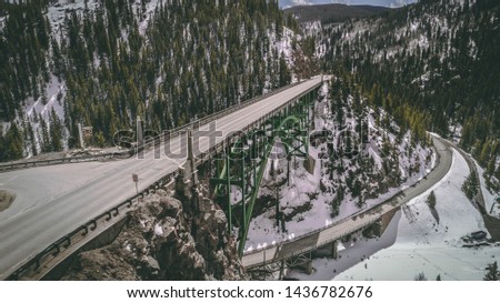 Aerial photo from a drone of the Red Cliff Bridge above Red Cliff, Colorado, on Tennessee Pass in the Mountains of Colorado in the winter, with snow and frozen Eagle River water in the canyon below. 
