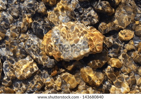 yellow stone in the river with sunbeam reflecting and moving water
