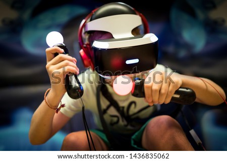 Young teenager boy using a Virtual reality headset with goggles and hands motion controllers in playing game zone. Modern technologies concept image. Royalty-Free Stock Photo #1436835062