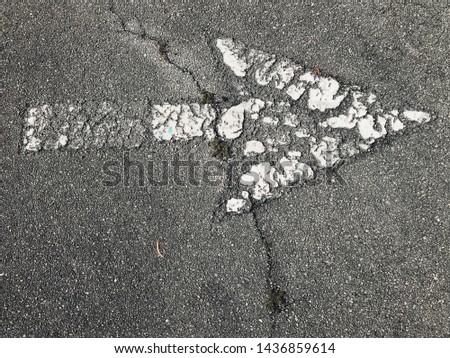 close up cracked old arrow sign on asphalt road