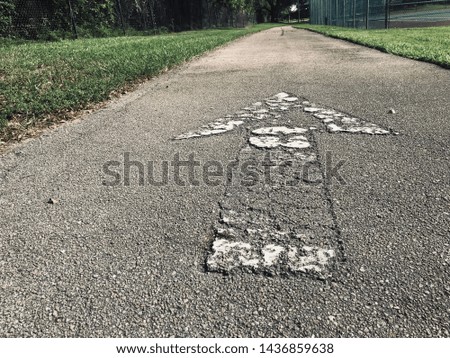 close up cracked old arrow sign on asphalt road