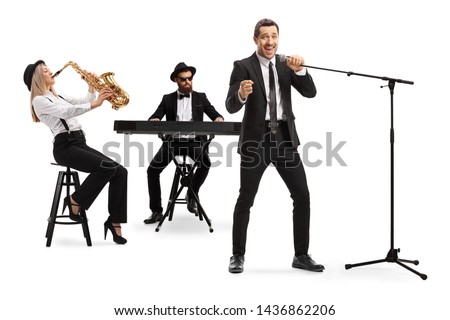 Full length shot of a woman playing sax, man playing a keyboard and a male singer singing on a microphone isolated on white background