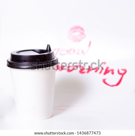 coffee in a paper Cup and a kiss print with bright lipstick and lipstick inscription good morning on a white background