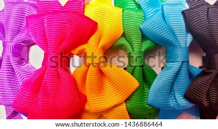 Row of different colored decorative hair bows overlapping from left to right on a white background.