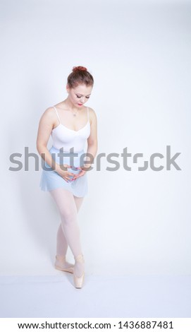 cute caucasian girl in ballet clothes learning to be a ballerina on a white background in the Studio. plus size young woman dreams of being a dancer.