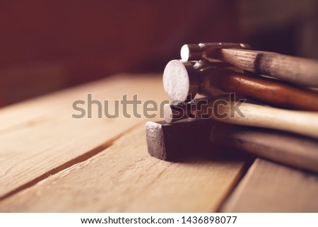 old vintage hammers and hallmark steel punches on a rustic wooden workbench of a goldsmith against a dark background, selected focus, narrow depth of field