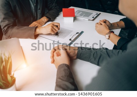 Real estate agents holding stamp for submit documents for customers to sign for a sale contract,real estate concept.
