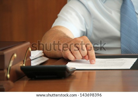 Hand of businessman at desk with document point finger on paper. Shallow depth of field.
