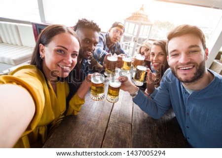 Happy multiracial group of friends taking a selfie drinking a beers at party 