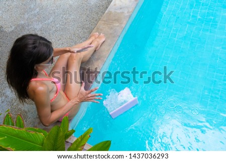 woman sits by the pool and drops the laptop into the water. The girl is resting on a minicomputer. selective focus.