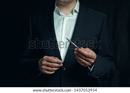 Businessman holding a silver pen while explaining or presenting	