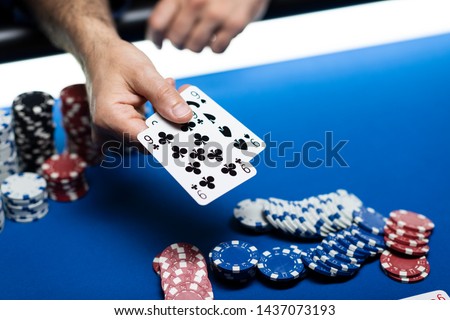 Man playing Texas Hold 'em poker at Casino, he is holding two cards Royalty-Free Stock Photo #1437073193