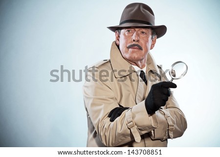Retro detective man with mustache and hat. Holding magnifying glass. Studio shot. Royalty-Free Stock Photo #143708851