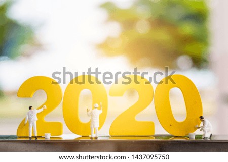 Miniature people : Worker team coloring wooden  number 2020 with blurred tree background