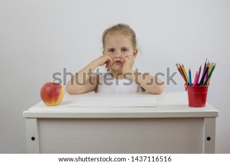 Girl preschooler at her desk with a sad look