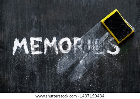 Mental issues concept: hand written word "memories" wiped off the black wood background. Top view of a crumbling phrase on a blackboard associated with memory decline, old age