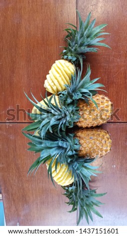Picture of sweet fruit pineapple that is still intact and which has been peeled with its shadow in a mirror